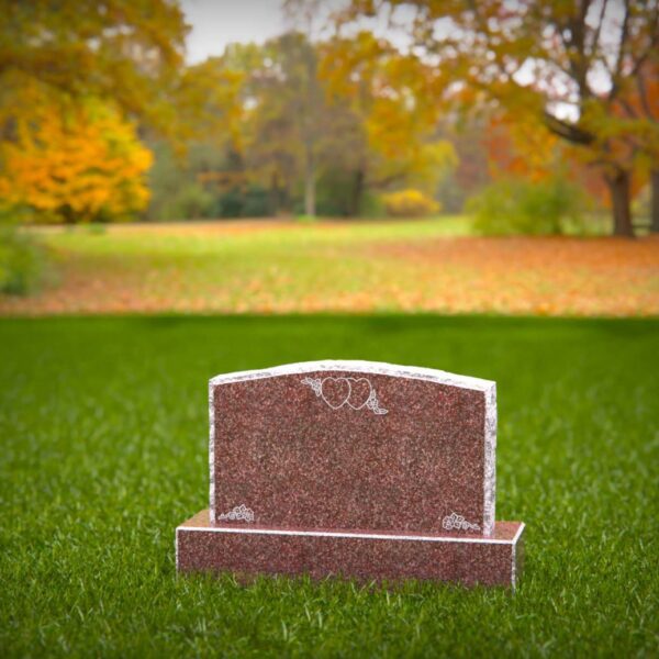 Small pink granite companion headstone in cemetery setting