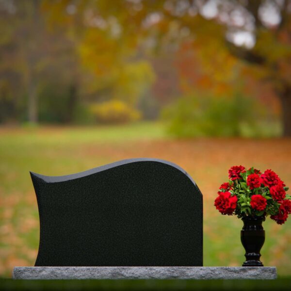 Polished black flat headstone with flower vase in cemetery landscape